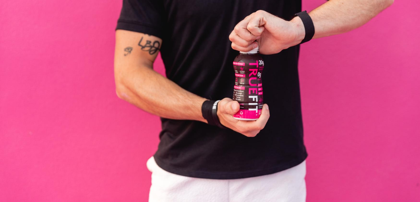 Man holding TrueFit ready-to-drink meal replacement shake, meal replacement shakes for weight loss