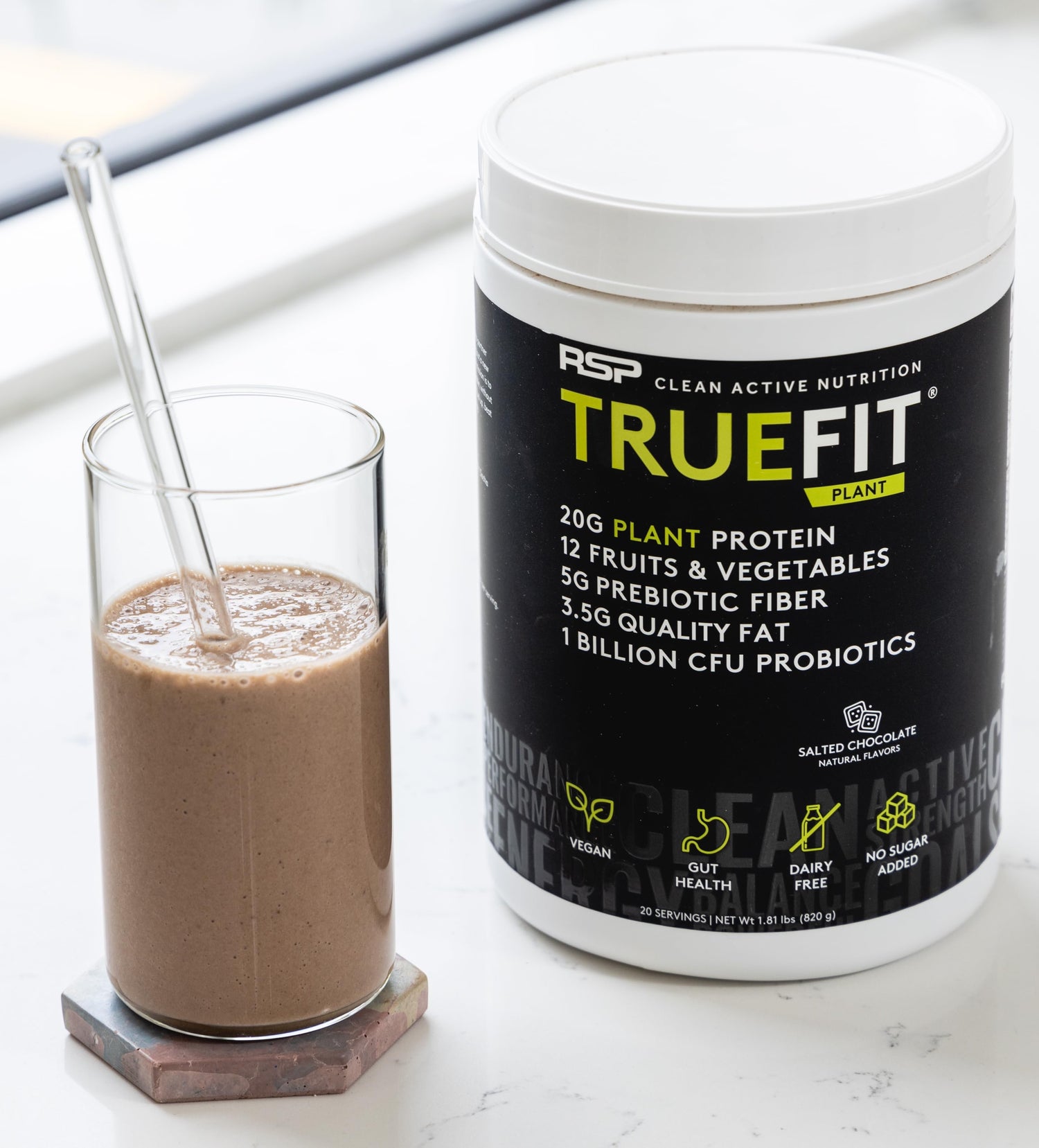 A TrueFit meal replacement shake next to a container of Salted Chocolate TrueFit Plant