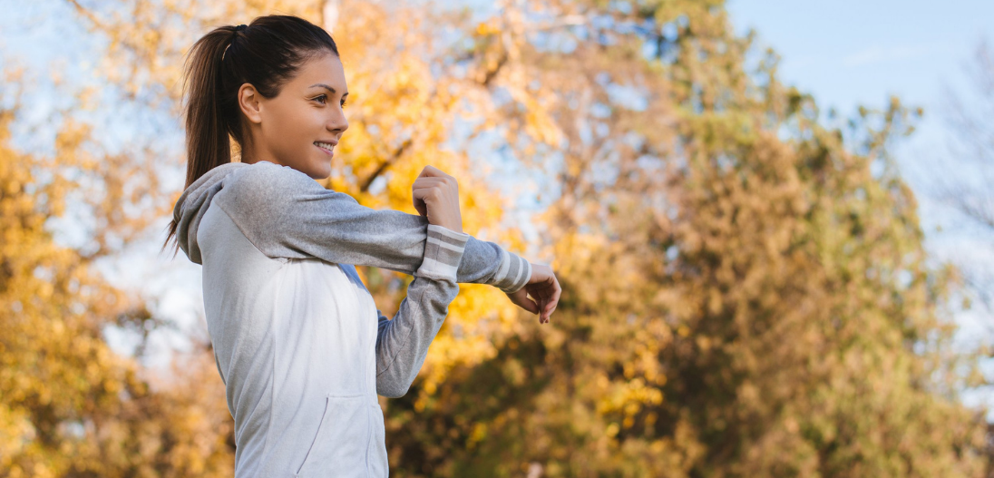 Woman stretching with fall foliage in the background