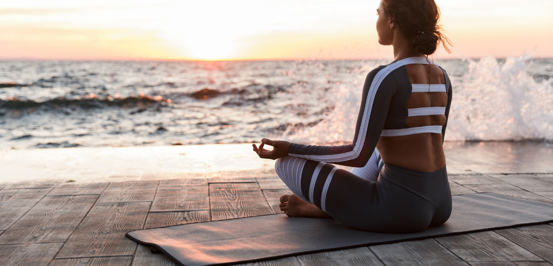 Woman meditating after yoga on a beach for stress relief
